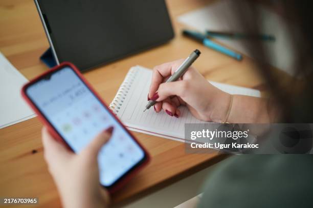 young woman using mobile phone to calculate her home budget. - educational subject stock pictures, royalty-free photos & images