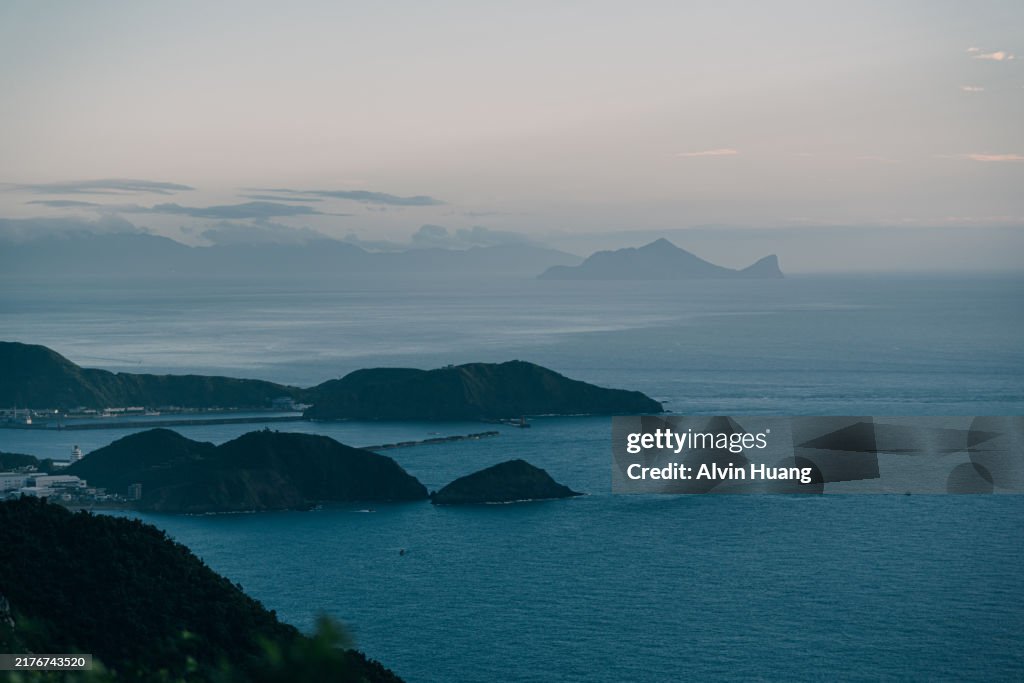 A high vantage point in Yilan County, Taiwan, provides a sweeping view of the famous Guishan Island, its turtle-like shape emerging from the blue ocean, creating a picturesque contrast with the surrounding waters.