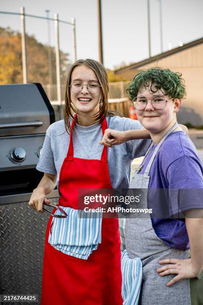 confident teens posing behind bbq at hot dog cart - teenagers only stock pictures, royalty-free photos & images