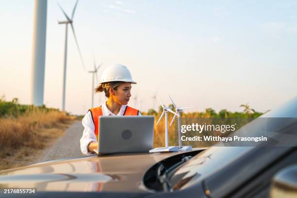 engineer using laptop in wind farm with mini turbine model - sustainable business stock pictures, royalty-free photos & images