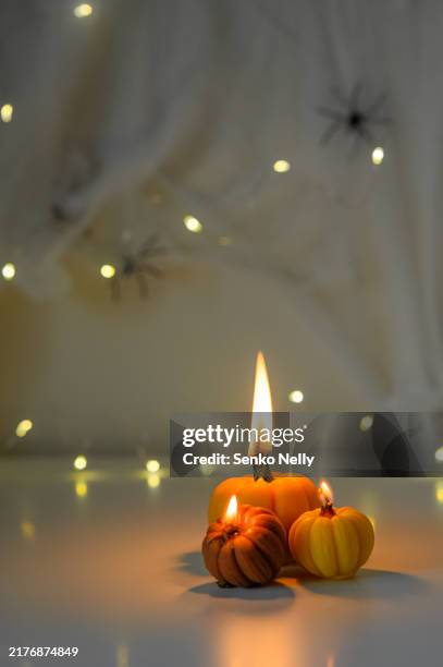 small pumpkin candles lit and glowing on a reflective surface - candlelight date stock pictures, royalty-free photos & images