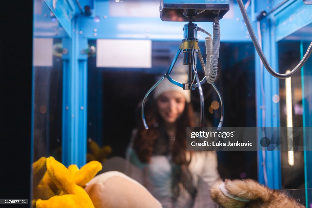 Young woman playing a claw machine in the arcade