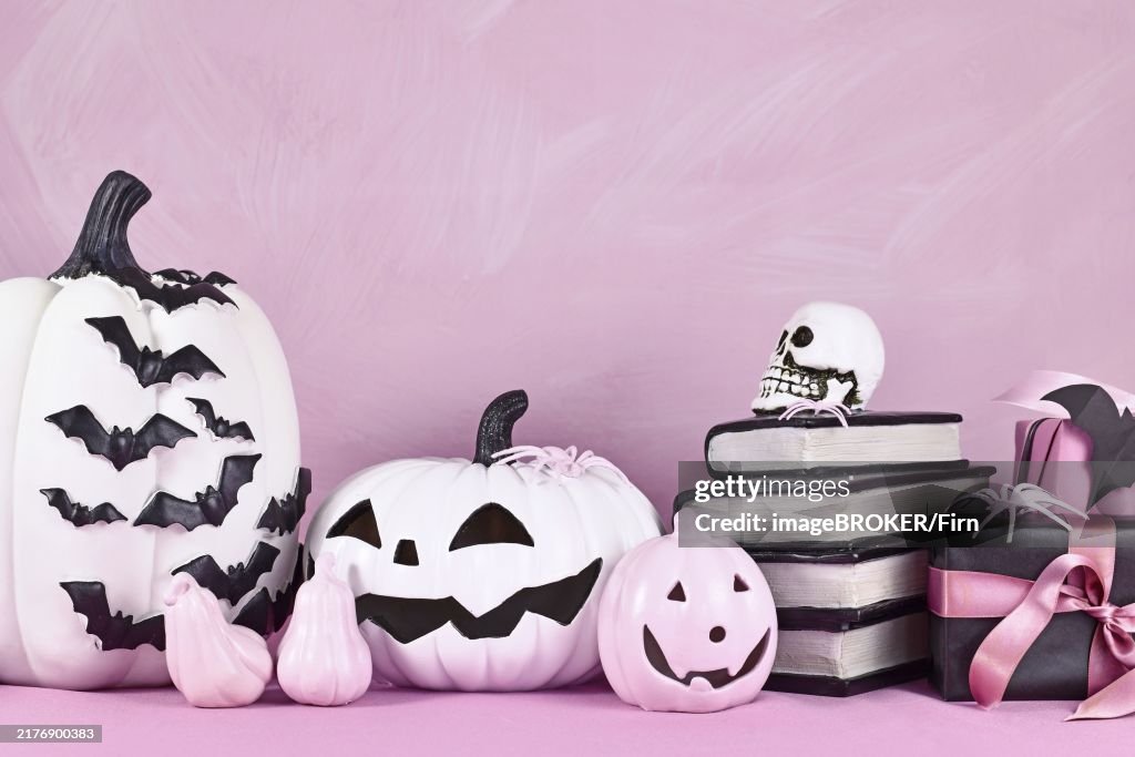 Pink Halloween decor with black and white pumpkins, spell books and spiders with copy space