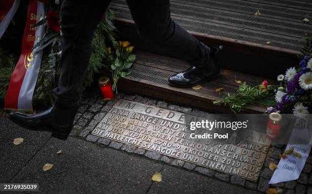 Man steps over a memorial plate for the victims of the 2019 shooting in front of the 'Kiez Doener' kebab shop in Halle , eastern Germany, on October...