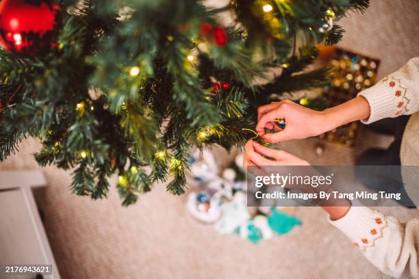 a close-up shot of hands decoration decorating christmas tree at home in festive holiday - decorating stock pictures, royalty-free photos & images