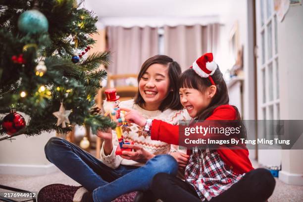 cheerful sister sharing holiday joy by the christmas tree at home - sister stock pictures, royalty-free photos & images