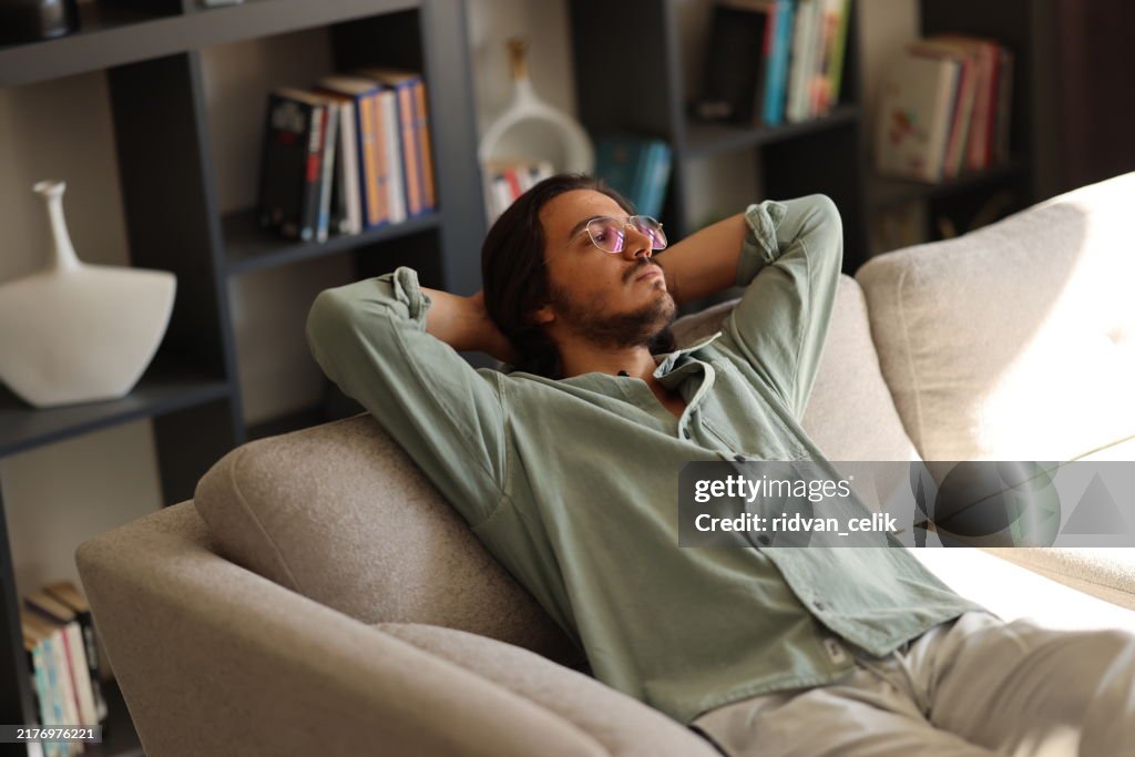 Pensive young man lying on sofa at home