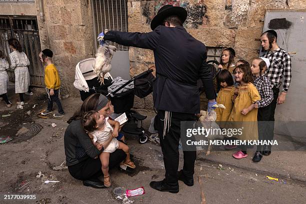 An ultra-Orthodox Jewish man swings a chicken over his family during the Jewish ritual of Kapparot in Jerusalem's Mea Shearim neighbourhood on...