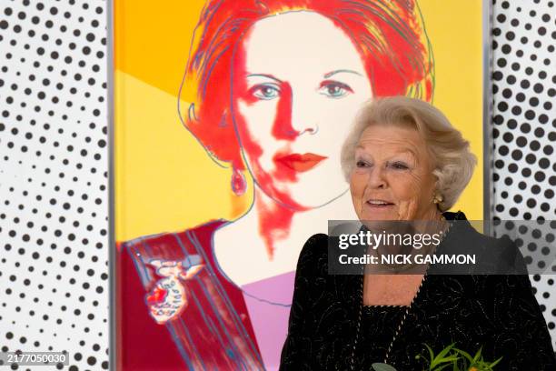 Princess Beatrix of the Netherlands poses in front of her portrait made by US artist Andy Warhol as she attends the preview of 'Queens by Andy...