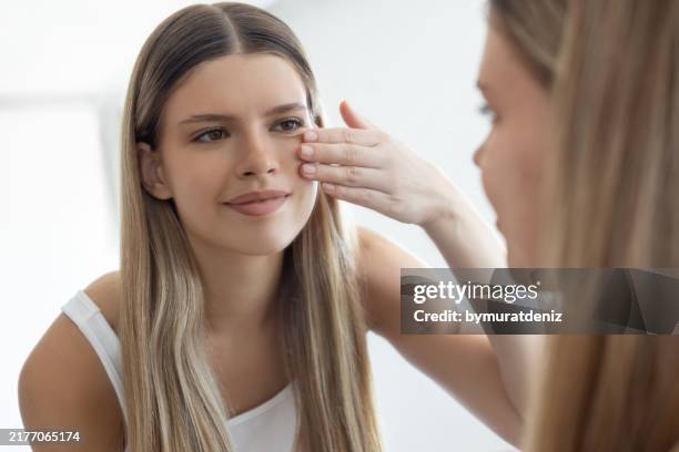 attractive young woman touching her skin - cheek stock pictures, royalty-free photos & images