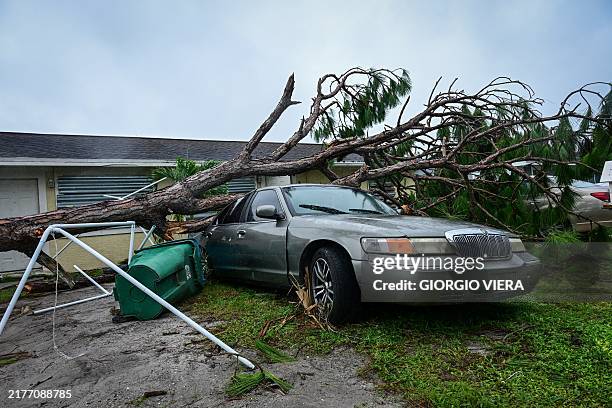 Fallen tree sits on a car in Lakewood Park, Florida, after a tornado hit the area and caused severe damage as Hurricane Milton swept through Florida...