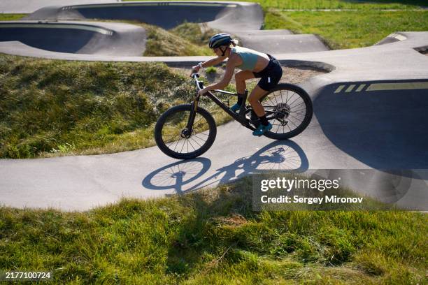 cyclist taking a sharp turn on pump track in sunny weather - air pump stock pictures, royalty-free photos & images