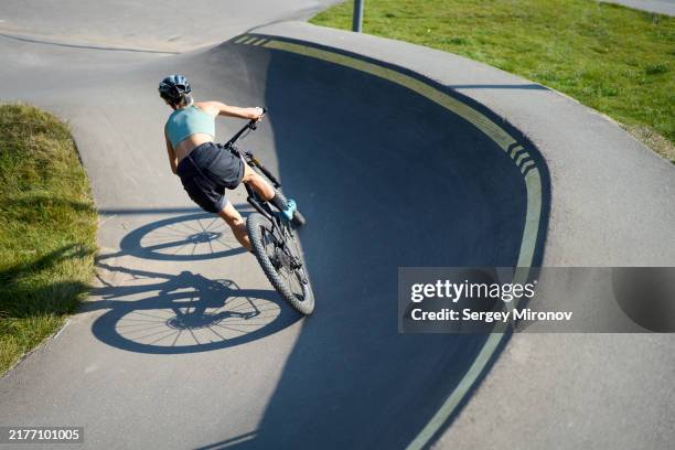 cyclist navigating steep curve at outdoor pump track - luftpumpe stock-fotos und bilder