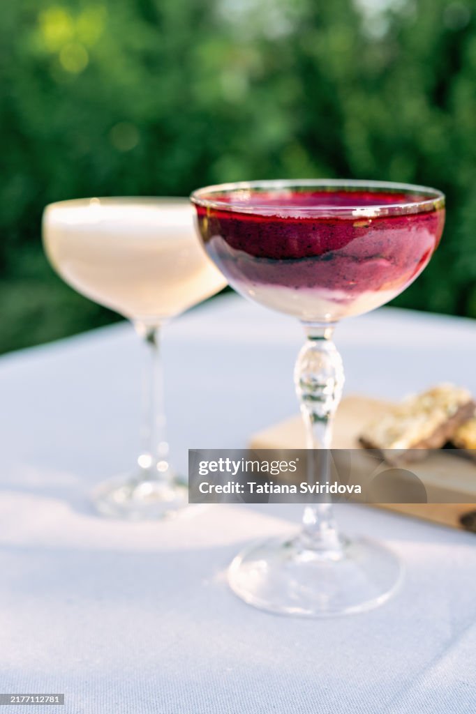 Cocktail glasses with fruit smoothie mocktail on a garden table