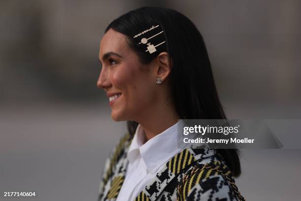 Fashion week guest is seen wearing a green, black and white patterned dress with a white blouse, hair clips and black sunglasses, as well as Chanel...
