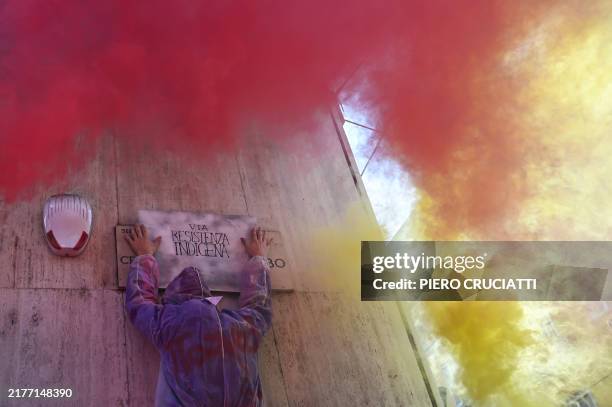 An activist places a banner reading 'Indigenous resistance' over a street name sign during the Fridays For Future demonstration in Milan, on October...