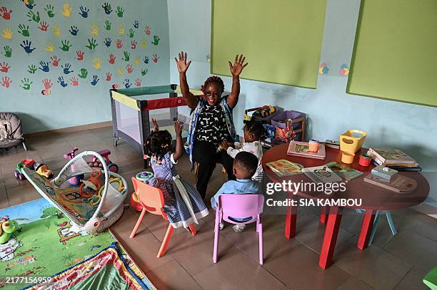 Preschool teacher plays with children in the nursery of the Papyrus school group in the popular commune of Yopougon in Abidjan on October 3, 2024....
