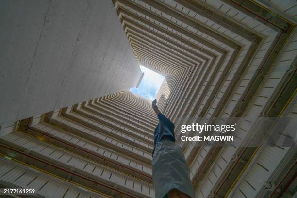 a man stands under a square roof, exploring the possibility of an exit, a concept expressing dilemma and a way out - effet de perspective photos et images de collection
