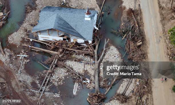 An aerial view shows people walking past a destroyed church in the aftermath of Hurricane Helene flooding on October 6, 2024 in Swannanoa, North...