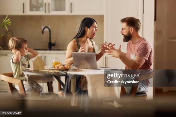 frustrated parents arguing in front of their small son in dining room. - hand to ear stock pictures, royalty-free photos & images