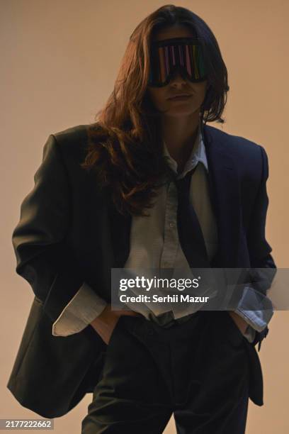 stylish model poses confidently in a sharp black suit with ski goggles. - completo da uomo foto e immagini stock