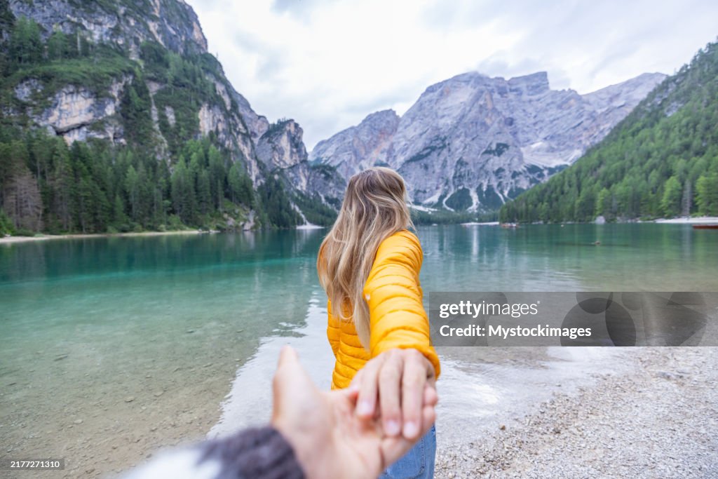 Couple Holding Hands by a Mountain Lake in Scenic Landscape