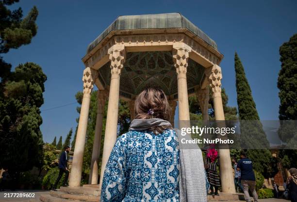 An Iranian woman who is not wearing a mandatory headscarf stands in front of the tomb of the 14th-century Iranian poet, Hafez, in Shiraz, Iran, on...