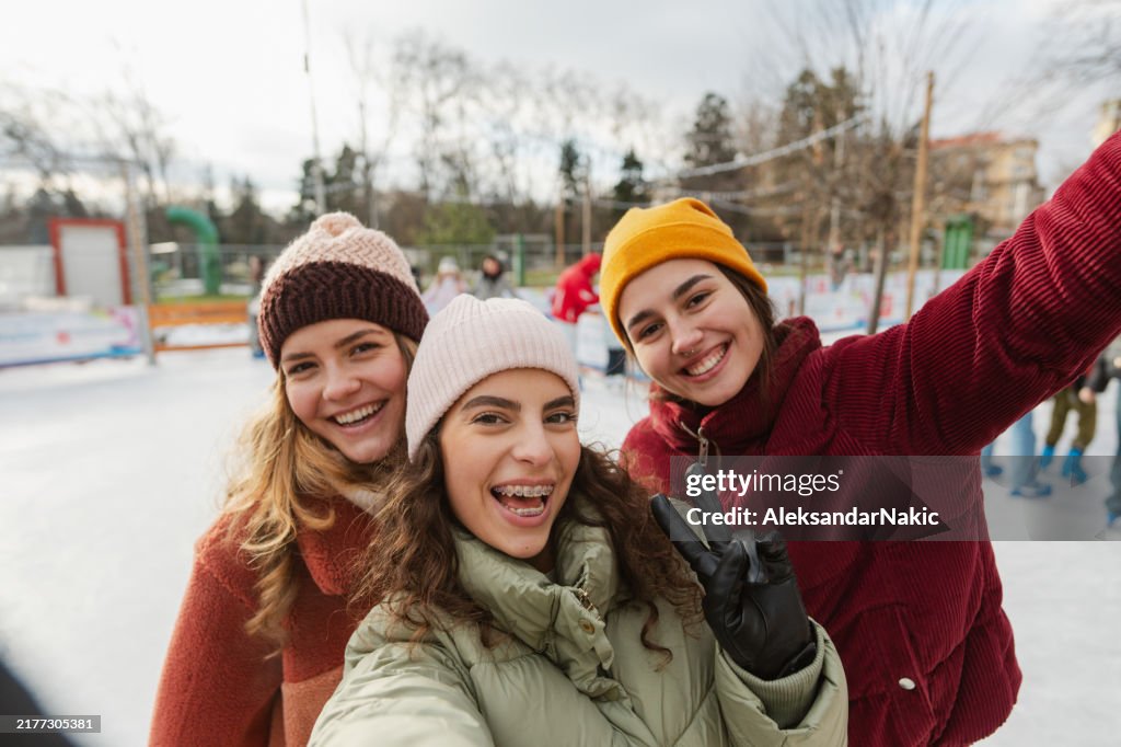 Young girls are taking selfies on the ice skate rink