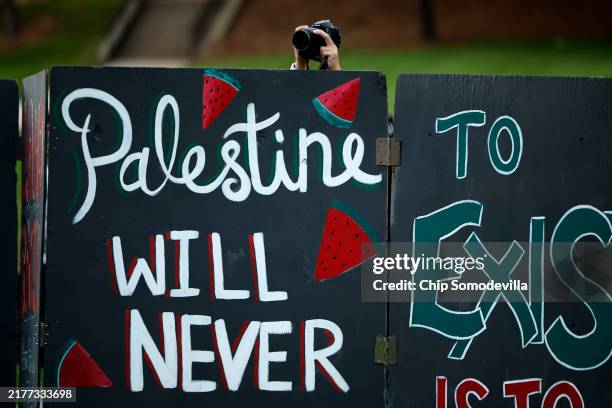 Photographer reaches over a sign board during a vigil organized by the Students for Justice in Palestine along McKeldin Mall in the heart of the...