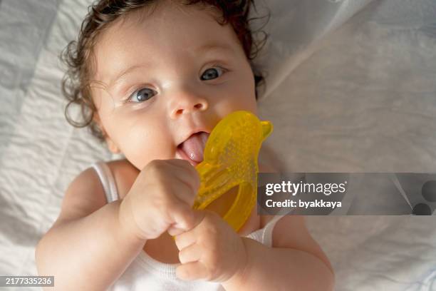baby using teether yellow silicone teething toy. - teething ring stock pictures, royalty-free photos & images
