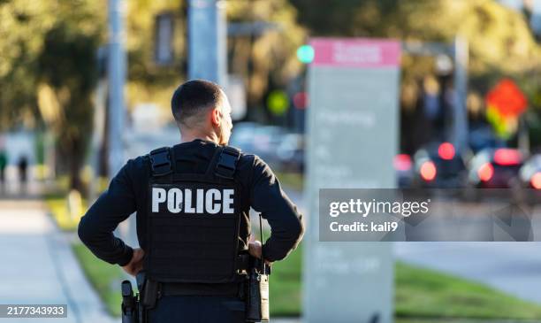 hispanic police officer walking on a sidewalk - police photos et images de collection