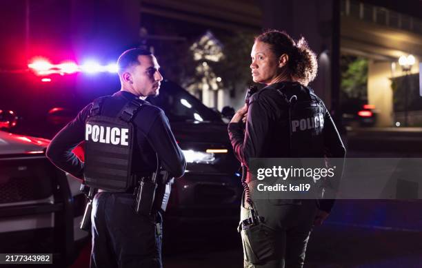 Two Multiracial Police Officers Working Outdoors At Night High-Res Stock Photo