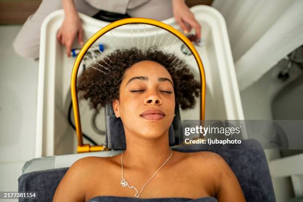 entspannte frau, die die haarwäsche im salon genießt - kopf an kopf stock-fotos und bilder