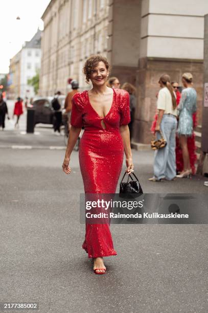 Renia Jaz wears long red maxi sequin dress and black bag outside the Rotate show during day four of the Copenhagen Fashion Week SS25 on August 08,...
