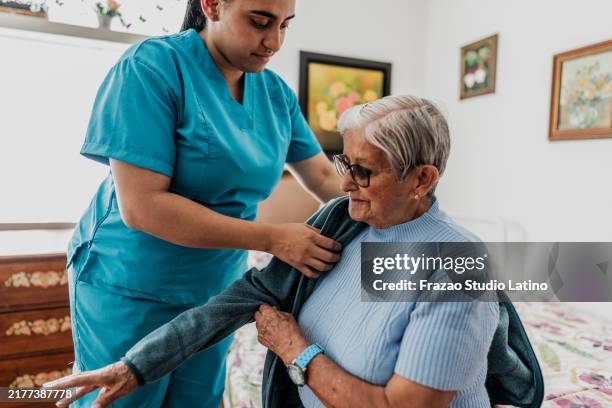 caregiver helping senior woman to get dressed at home - getting dressed stock pictures, royalty-free photos & images