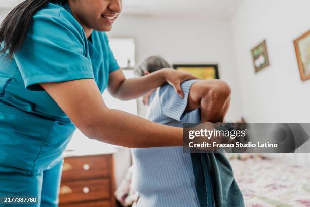 cuidadora que ayuda a una anciana a vestirse en casa - vestirse fotografías e imágenes de stock