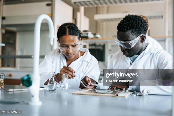 male and female students doing science experiment in laboratory - biochemistry stock pictures, royalty-free photos & images