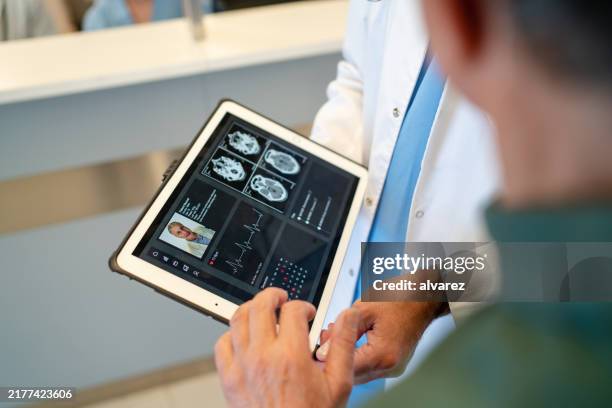 close-up of doctor reviewing report with patient using digital tablet in hospital - medisch dossier stockfoto's en -beelden