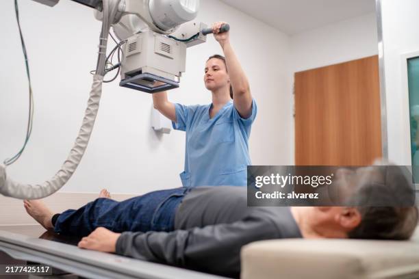 technician conducting x-ray of senior patient's leg - imagem de raios x imagens e fotografias de stock