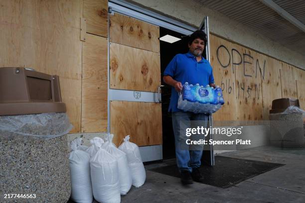 People walk in and out of a boarded-up 7-11 store as the state prepares for the arrival of Hurricane Milton on October 08 in St. Petersburg, Florida....