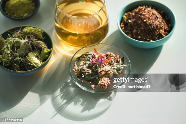 herbal tea, tea cup with various dried tea leaves and flowers shot from above on white table - dry herbs stock pictures, royalty-free photos & images