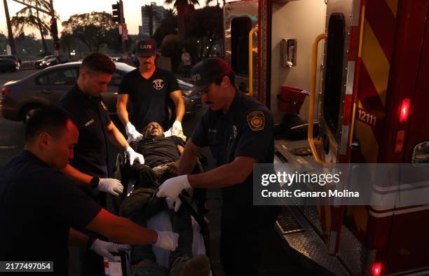 Emergency medical technicians and paramedics with Los Angeles Fire Station 11 prepare to take a man they just revived from a drug overdose to the...