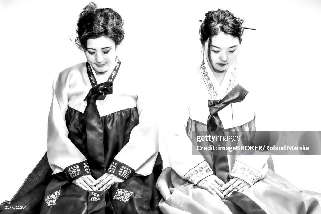Two seated woman in Korean traditional costume bowing their heads, Korean siblings in hanbok, sisters, Korea, black and white photo