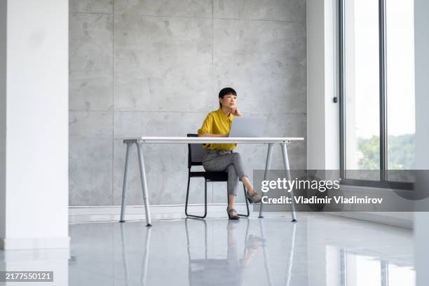 woman at modern desk, focused on work in bright minimalist office space - minimal art stockfoto's en -beelden