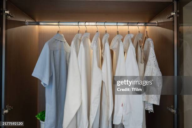 clothes neatly hanging in modern wooden wardrobe - rack stock pictures, royalty-free photos & images