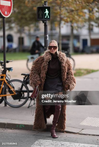 Leonie Hanne is seen wearing burgundy oversized shield frame sunglasses with wide temples from Stella McCartney, silver drop-shaped earrings from...
