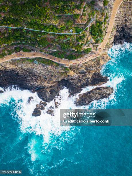 tourist walking in the romantic foot path called via dell'amore close to the village of riomaggiore and manarola, cinque terre national park, liguria, italy, europe - cinque terre foto e immagini stock
