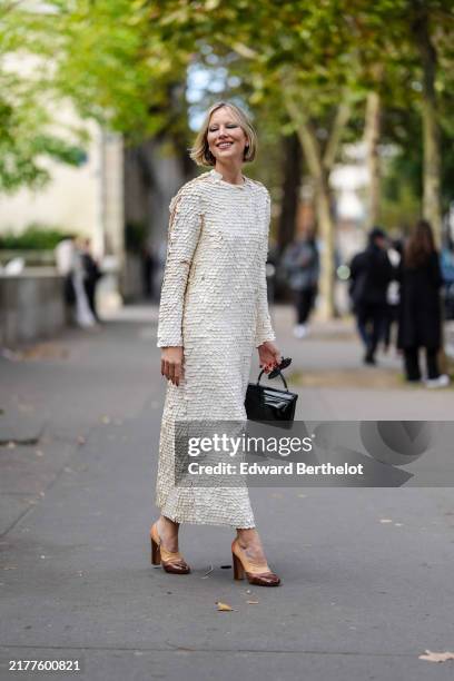Guest wears black sunglasses, a white long sequin dress, black leather Celine bag, brown leather high heels, during Womenswear Spring/Summer 2025 as...