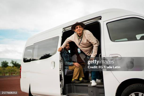 mid adult tour guide man getting out of van outdoors - bus tour guide stock pictures, royalty-free photos & images