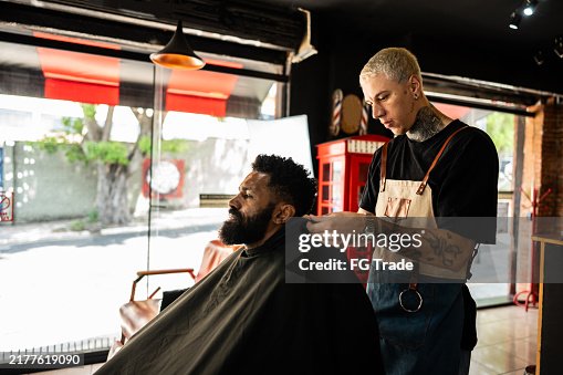 Barber putting a cape on the customer at a barber shop Barber putting a cape on the customer at a barber shop